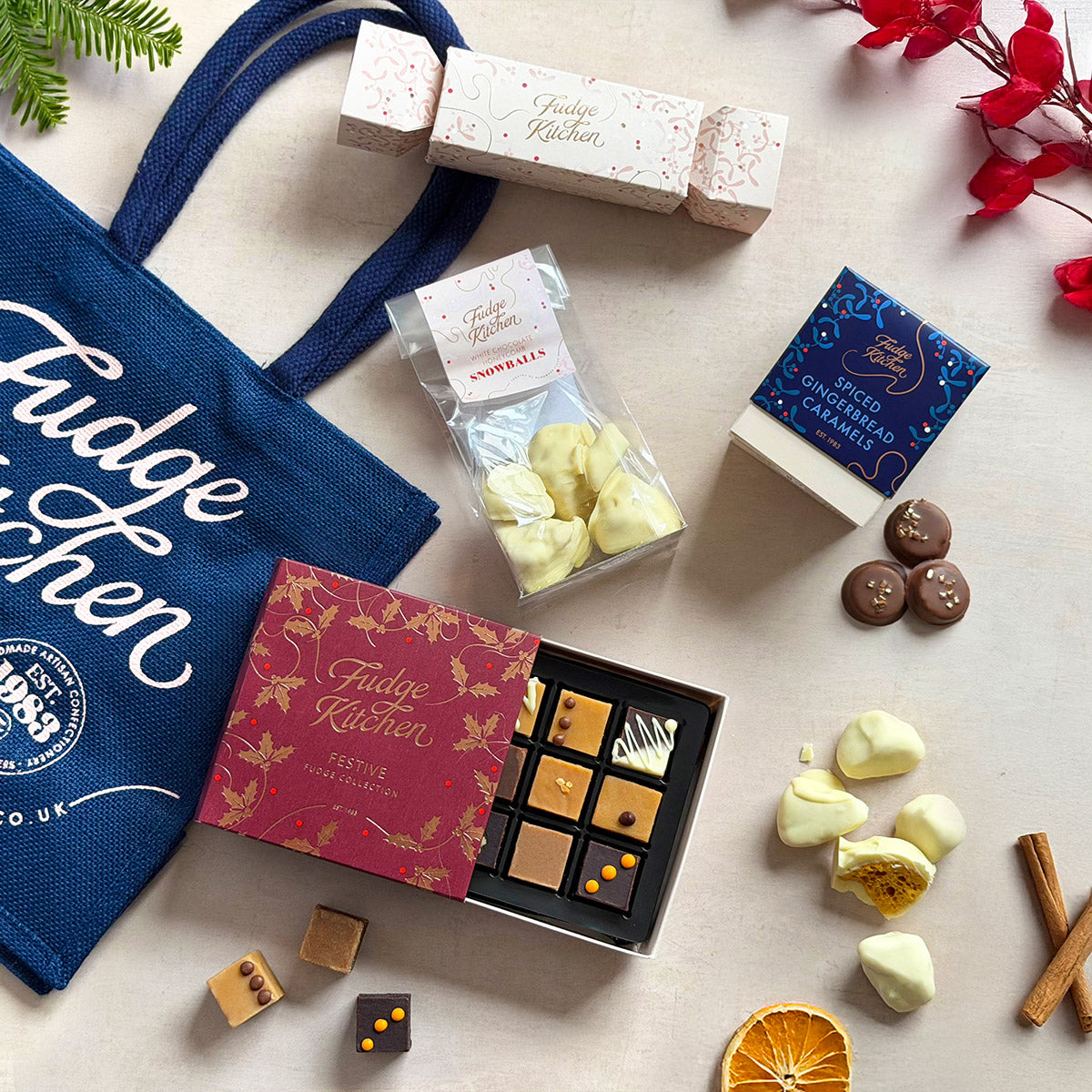 Assorted festive fudge and caramels from Fudge Kitchen on a light surface with a branded tote bag, perfect for holiday gifting.