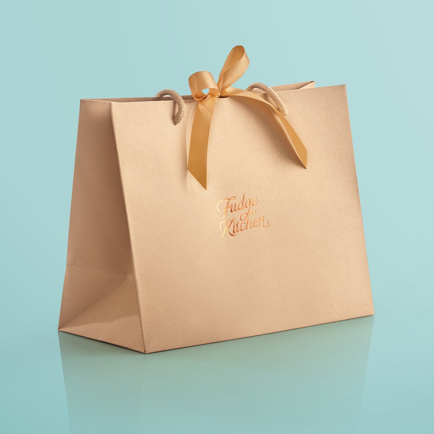 Elegant Fudge Kitchen gift bag with satin ribbon closure displayed on a light blue background, designed to beautifully present our handmade fudge for any special occasion.