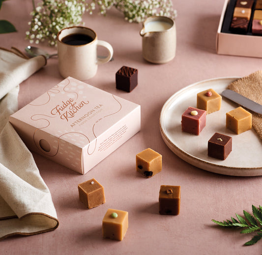 Afternoon Tea Selection box on a table with fudge pieces and coffee setup