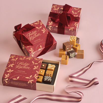 Fudge Kitchen festive fudge collection with red and gold packaging on a pink background