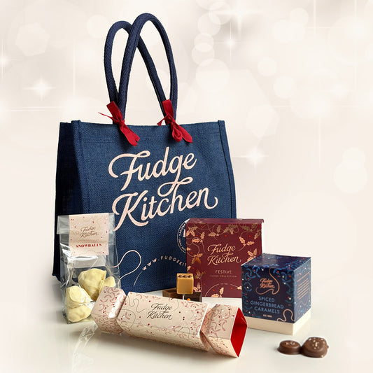 Fudge Kitchen tote bag with various festive fudge and caramels from Fudge Kitchen on a light surface, perfect for holiday gifting.