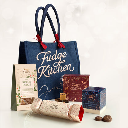 Fudge Kitchen tote bag with various festive fudge and caramels from Fudge Kitchen on a light surface, perfect for holiday gifting.