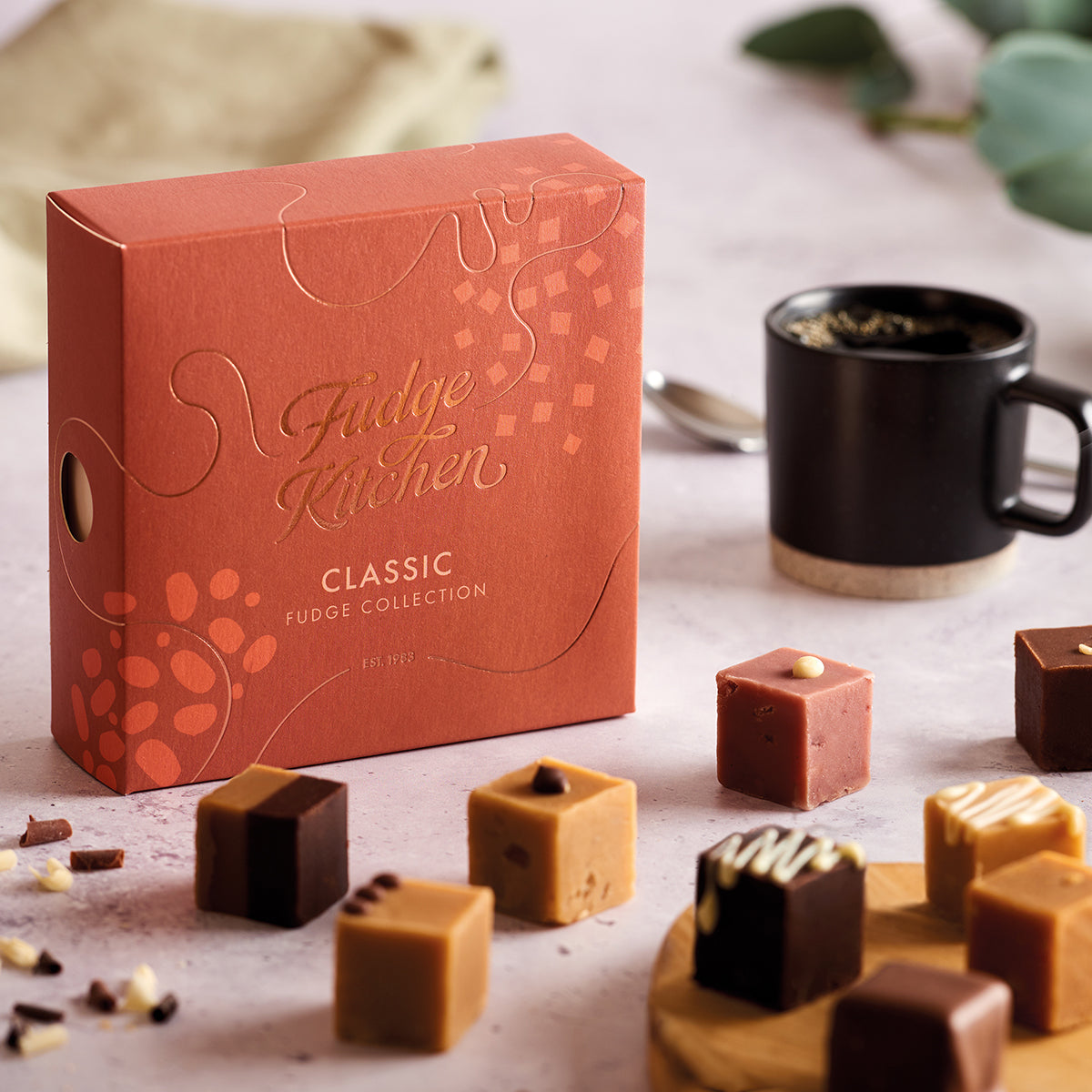 Fudge Kitchen Classic selection box featured in a table setting with artisan butter fudges displayed on a board and dining accoutrements.
