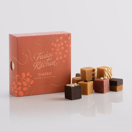 Fudge Kitchen, Classic Fudge Selection box, angled and featured on a light grey background. Artisan fudge flavours displayed in a stack beside the box