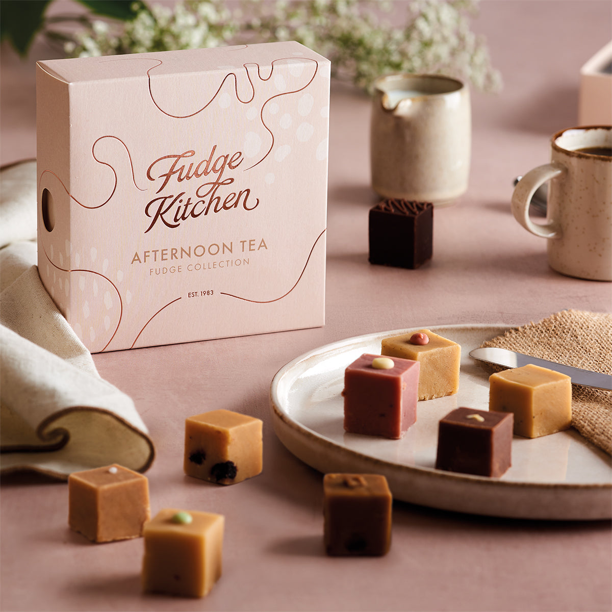 Fudge Kitchen Afternoon Tea selection box featured in a table setting with artisan butter fudges displayed on a plate and dining accoutrements.
