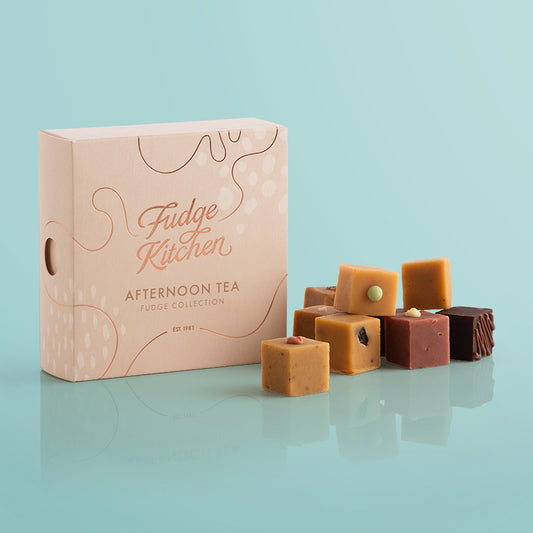 Fudge Kitchen, Afternoon Tea Fudge Selection box, angled and featured on a light blue background. Artisan fudge flavours displayed in a stack beside the box
