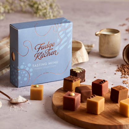 Fudge Kitchen Tasting Menu selection box featured in a table setting with artisan butter fudges displayed on a board and dining accoutrements.
