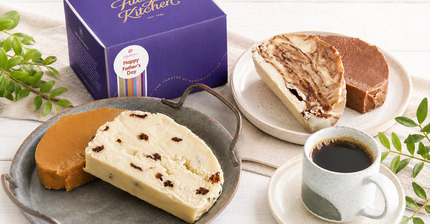 Four slices of Fudge on a plate with a cup of coffee and an indigo Fudge Kitchen gift box in the background.