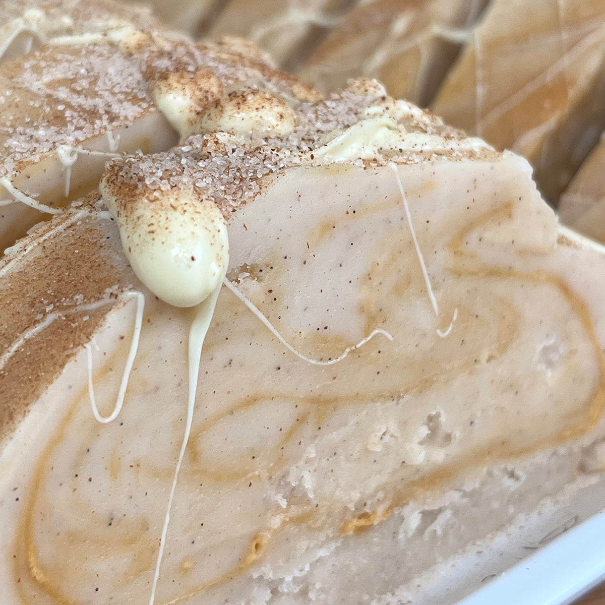 Close-up of a slice of cinnamon bun swirl fudge, topped with white drizzle and a sprinkle of brown cinnamon sugar.