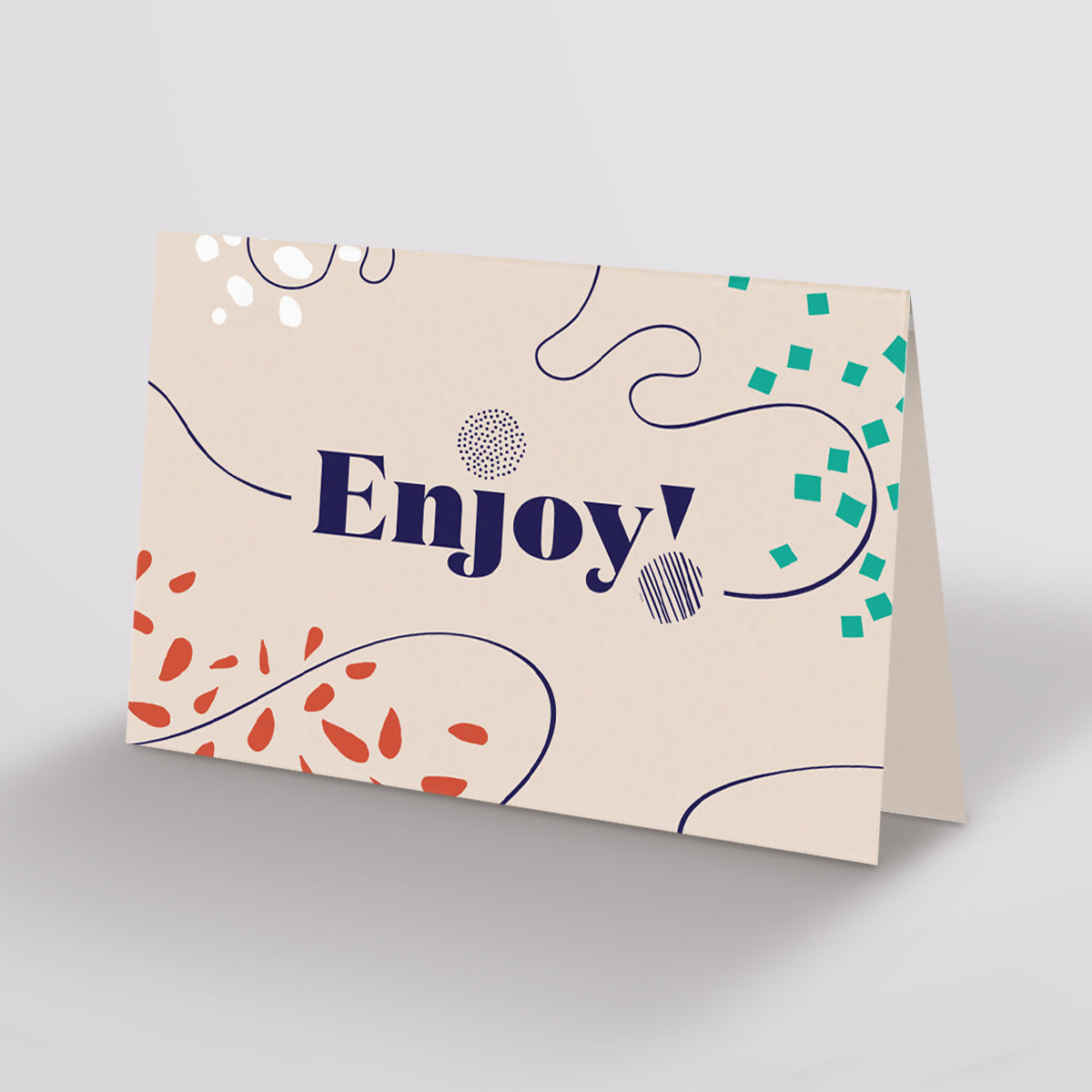 Small Gift Card on a grey background with Enjoy! written on a buff card with swirl decoration.