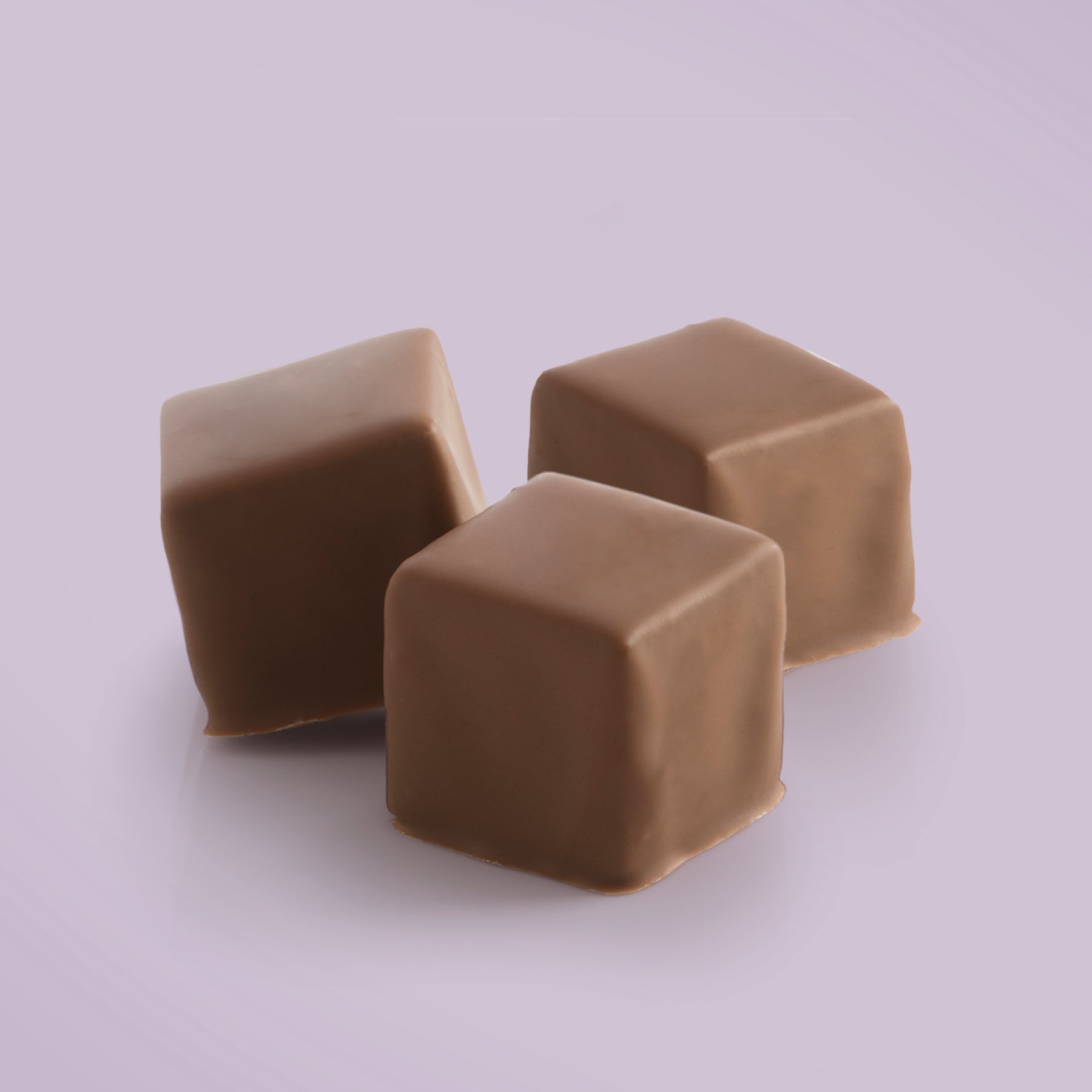 Close-up of Chocolate Coated Salted Caramel Fudge by Fudge Kitchen, displayed on a lavendar background.