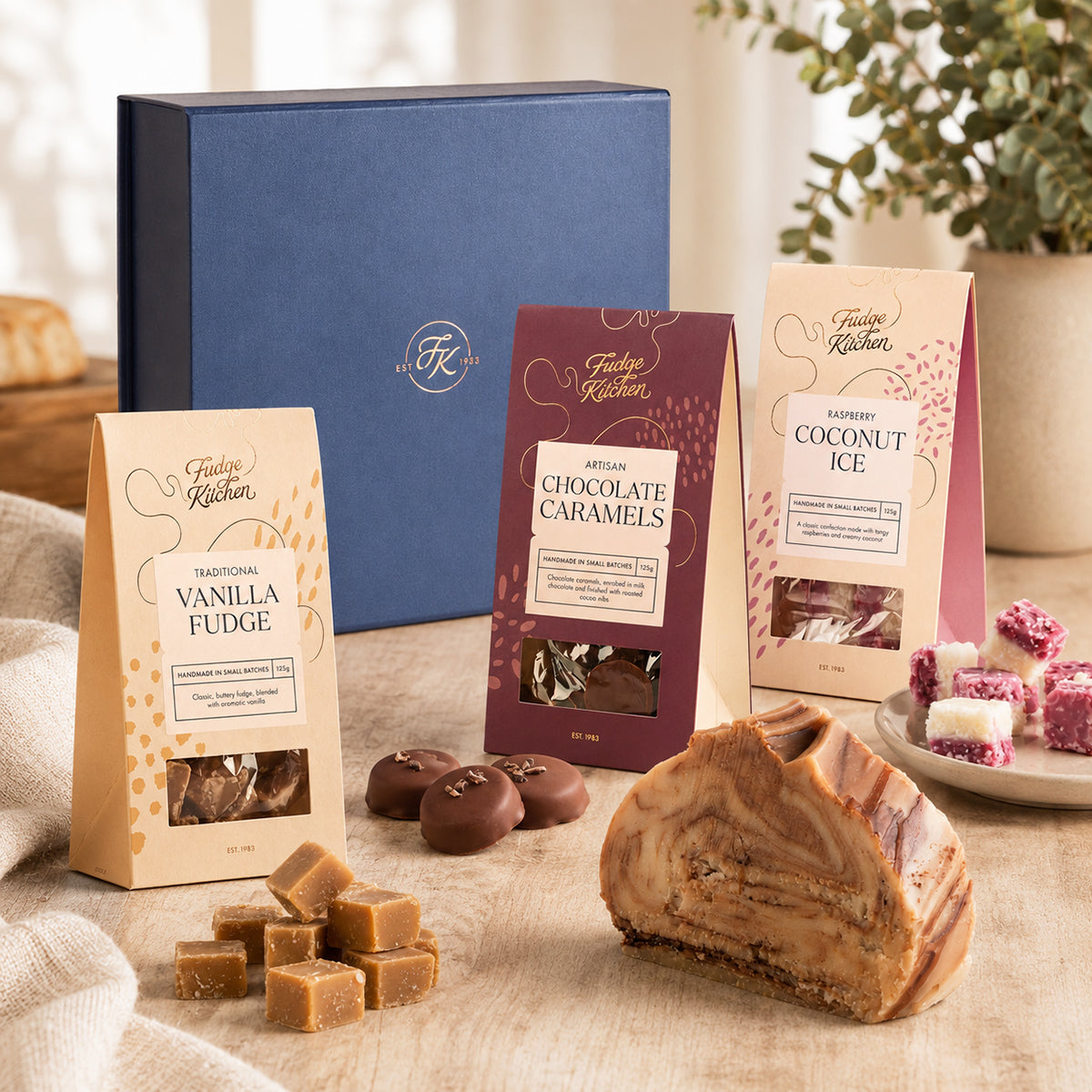 Assorted Fudge Kitchen confectionery items including fudge, caramels, and coconut ice on a wooden surface with a blurred background.