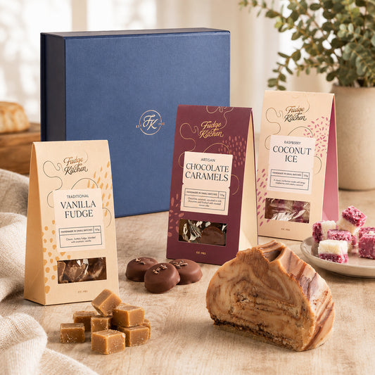 Assorted Fudge Kitchen confectionery items including fudge, caramels, and coconut ice on a wooden surface with a blurred background.
