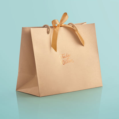 Elegant Fudge Kitchen gift bag with satin ribbon closure displayed on a light blue background, designed to beautifully present our handmade fudge for any special occasion. 