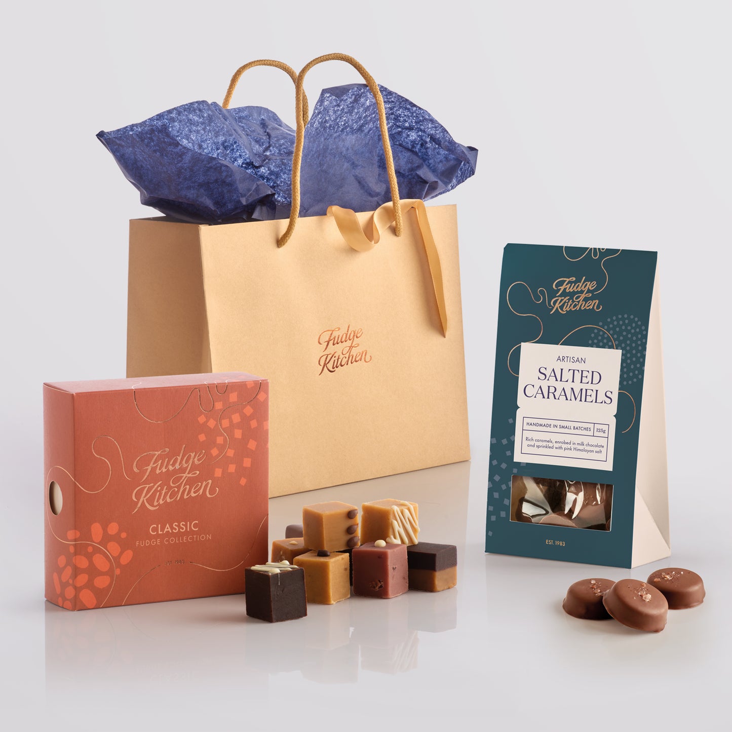 Assorted Fudge Kitchen confectionery items including fudge and caramels on a light blue background.