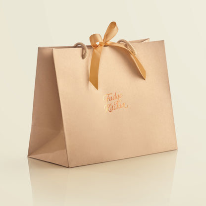 Elegant Fudge Kitchen gift bag with satin ribbon closure displayed on a lemon background, designed to beautifully present our handmade fudge for any special occasion. 