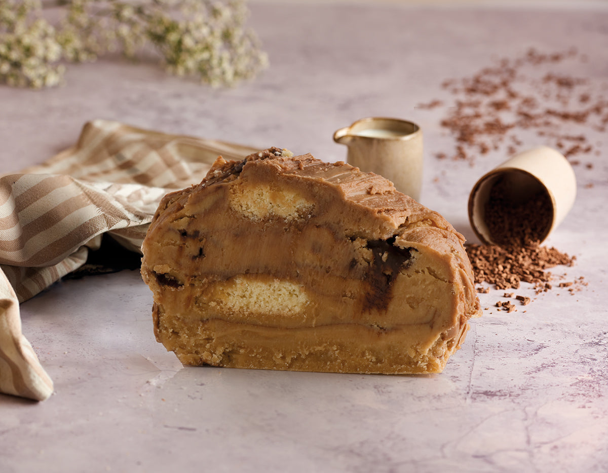 A slice of Millionaire's Shortbread fudge. Millionaire’s Shortbread in gloriously soft handmade fudge displayed on a table with chocolate pieces and cream jug.