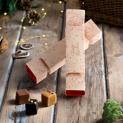 Luxury fudge crackers with decorative packaging on a wooden surface with Christmas flavour fudge pieces.
