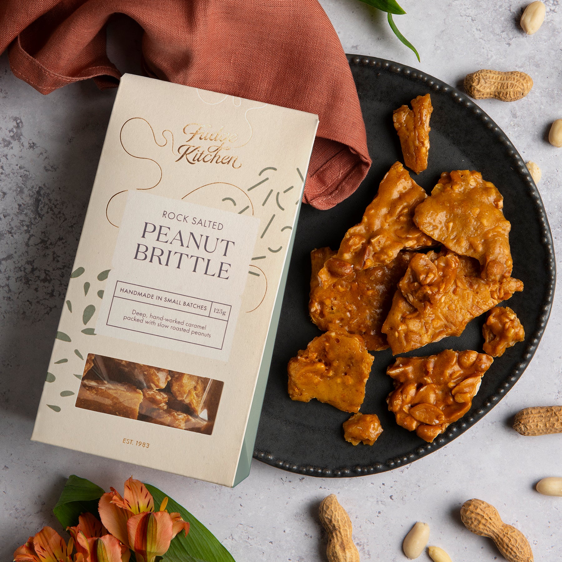 Rock Salted Peanut Brittle served on a rustic table setting. A lifestyle shot showcasing this nutty, crunchy treat for any occasion.
