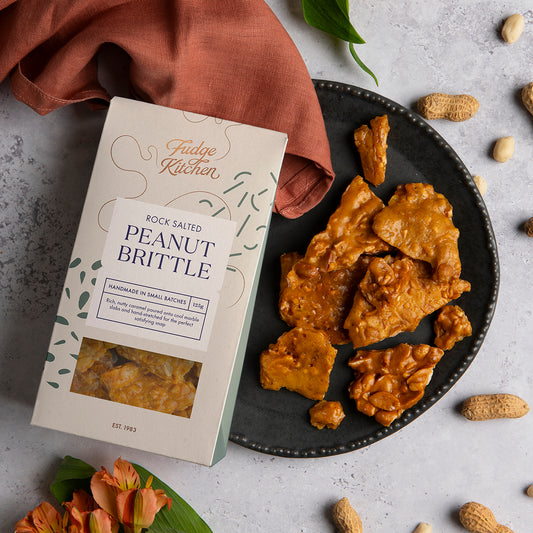 Rock Salted Peanut Brittle served on a rustic table setting. A lifestyle shot showcasing this nutty, crunchy treat for any occasion.