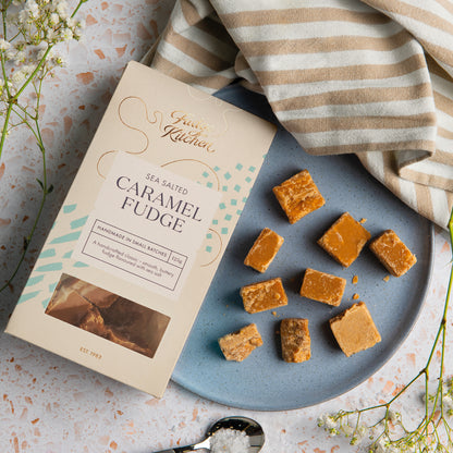 Fudge Kitchen sea salted caramel fudge on a plate with packaging and a striped cloth.