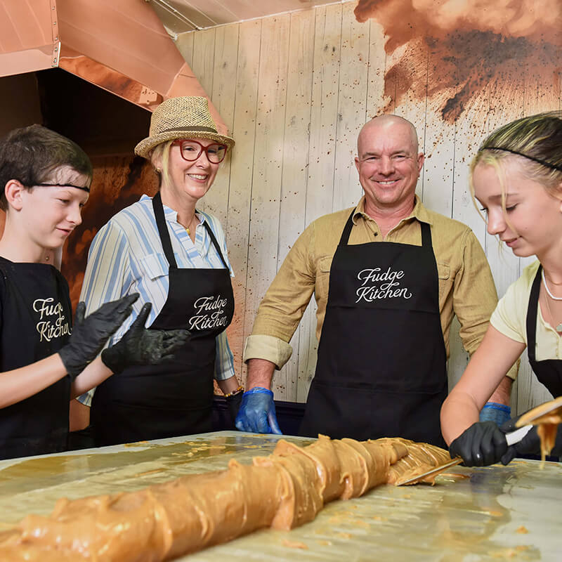 Group of people learning traditional fudge crafting techniques during a fun and interactive fudge making experience workshop.