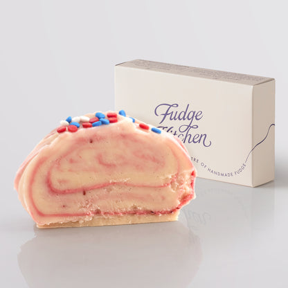 Fudge slice with colorful sprinkles next to a 'Fudge Kitchen' box on a light gray background