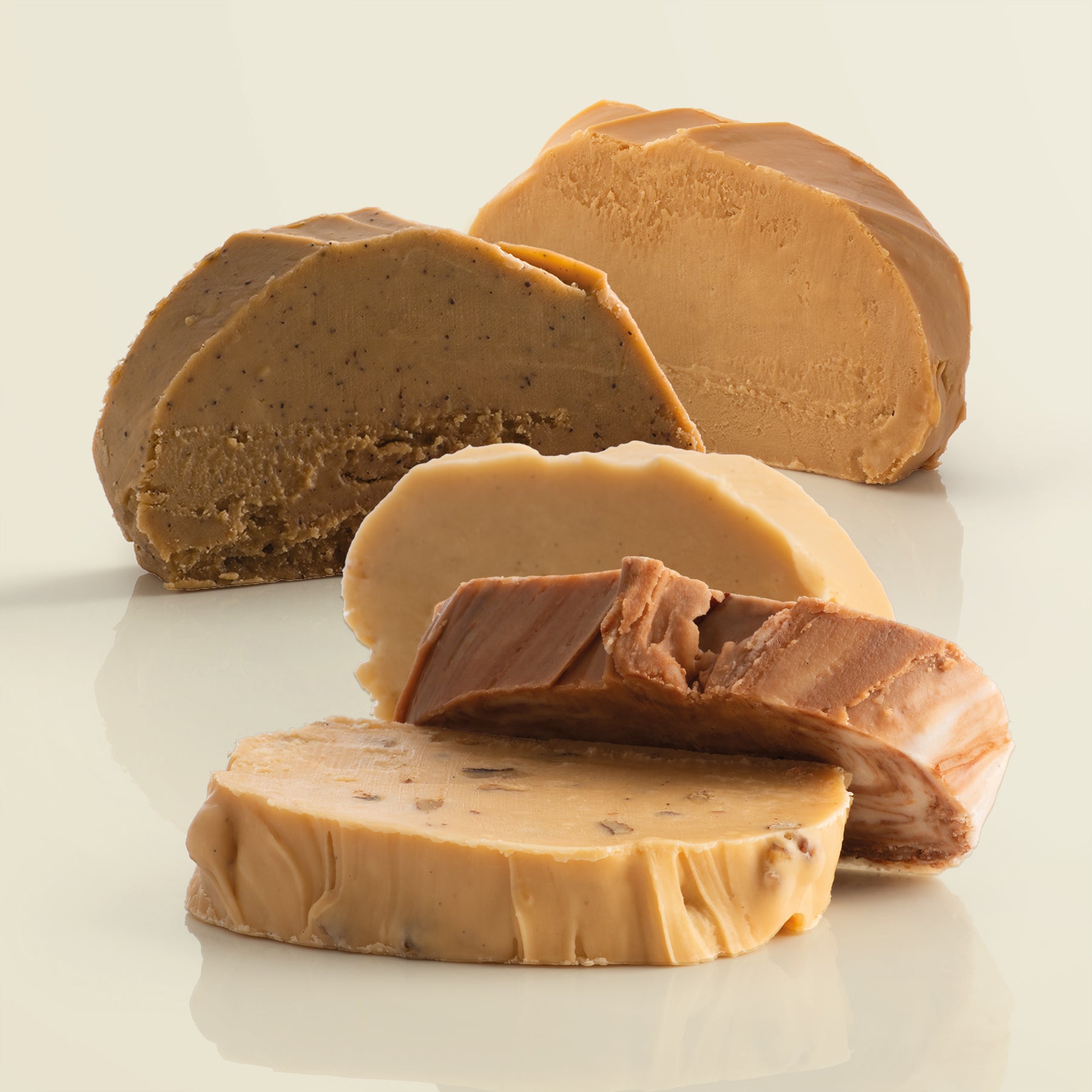 Five thick, fresh fudge slices on a reflective surface with a light yellow background.