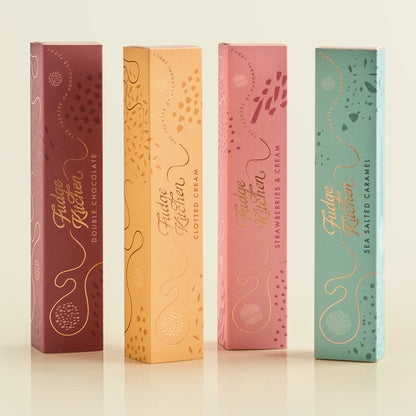 Four Fudge Kitchen fudge gift boxes in different flavors on a light background