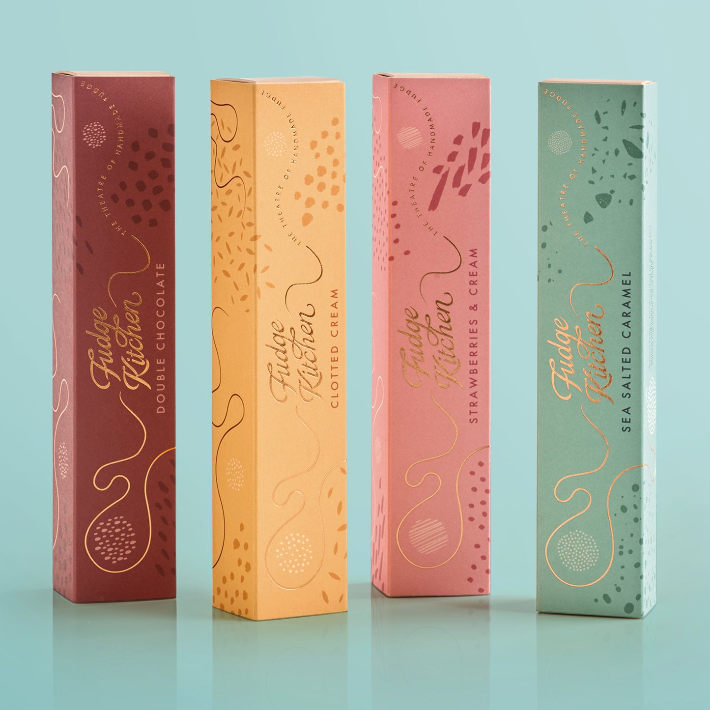 Four Fudge Kitchen fudge gift boxes in different colors on a light blue background