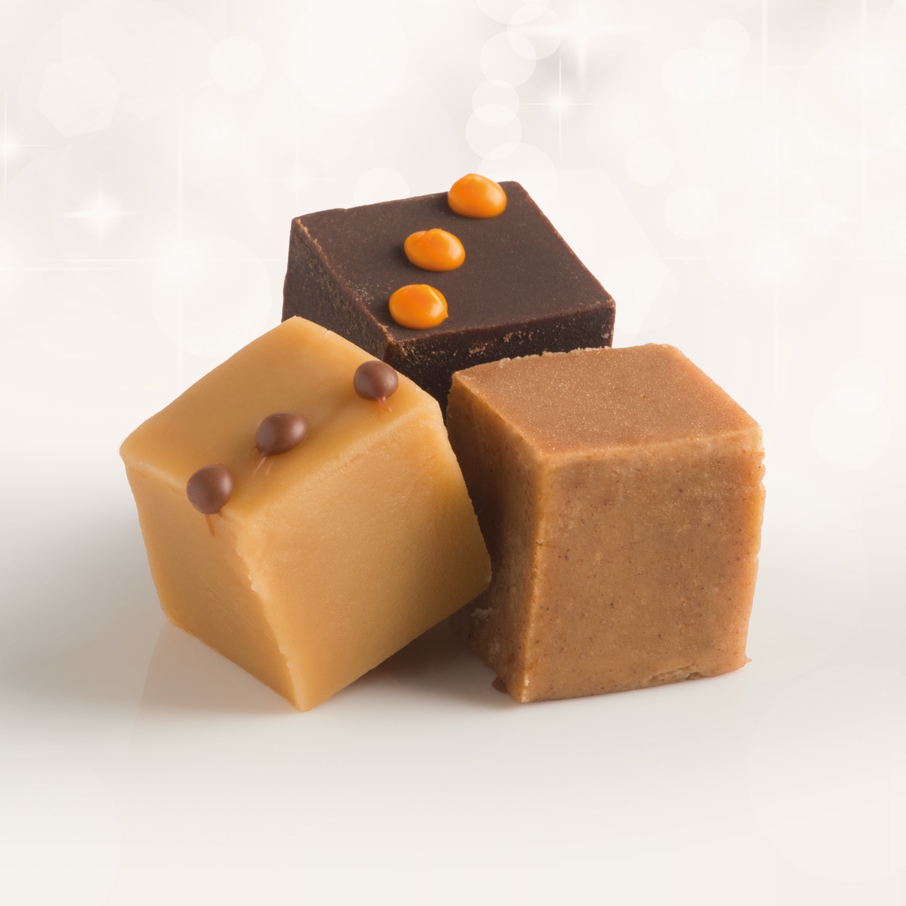 Three pieces of fudge in different flavours: Salted Caramel, Gingerbread, Chocolate & Orange on a white background.