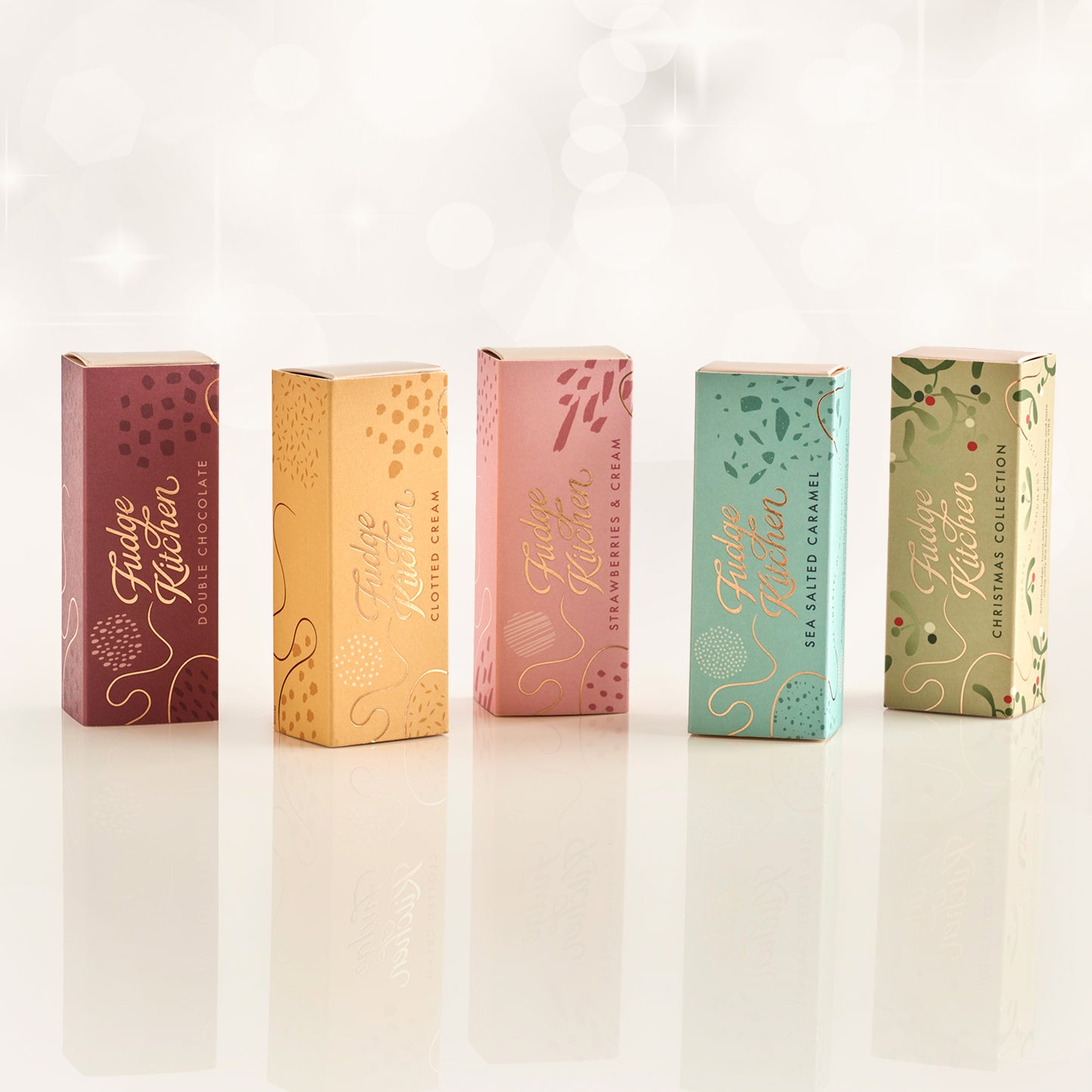 Five colourful fudge slim slider boxes of Fudge Kitchen fudge selections on a white background.