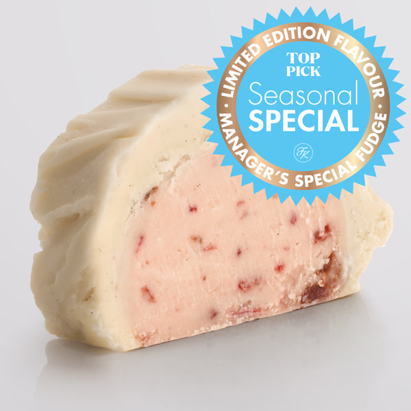 A slice of classic Strawberries & Cream Fudge showing the two layered fudge pairing a base of ripe strawberry fudge with a silky top tier of Madagascan vanilla fudge with a Seasonal Special badge.