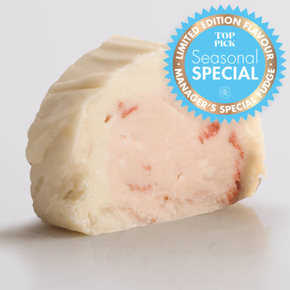 A slice of classic Strawberries & Cream Fudge showing the two layered fudge pairing a base of ripe strawberry fudge with a silky top tier of Madagascan vanilla fudge with a Seasonal Special badge.