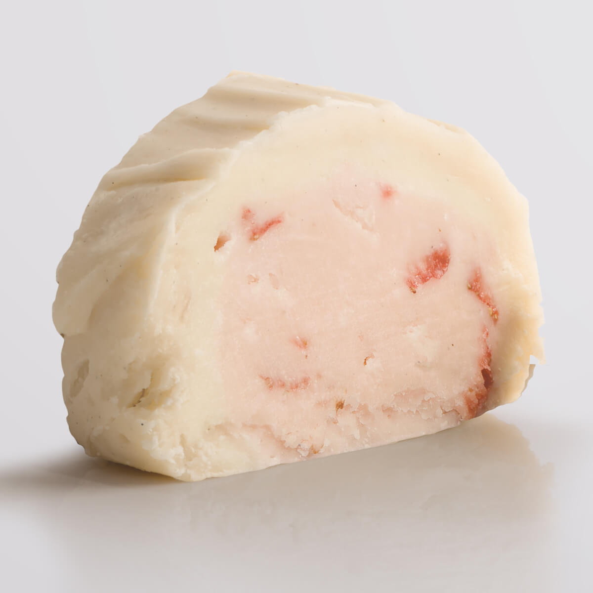 A slice of classic Strawberries & Cream Fudge showing the two layered fudge pairing a base of ripe strawberry fudge with a silky top tier of Madagascan vanilla fudge.