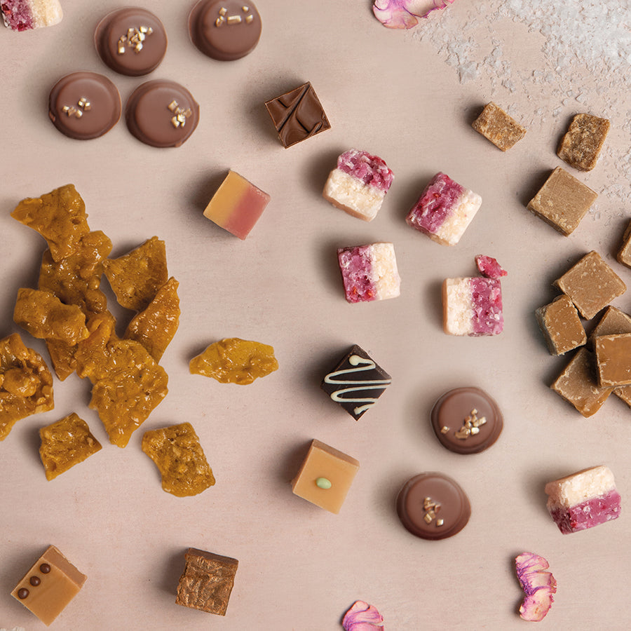 Assorted chocolates, caramels and fudges on a textured surface