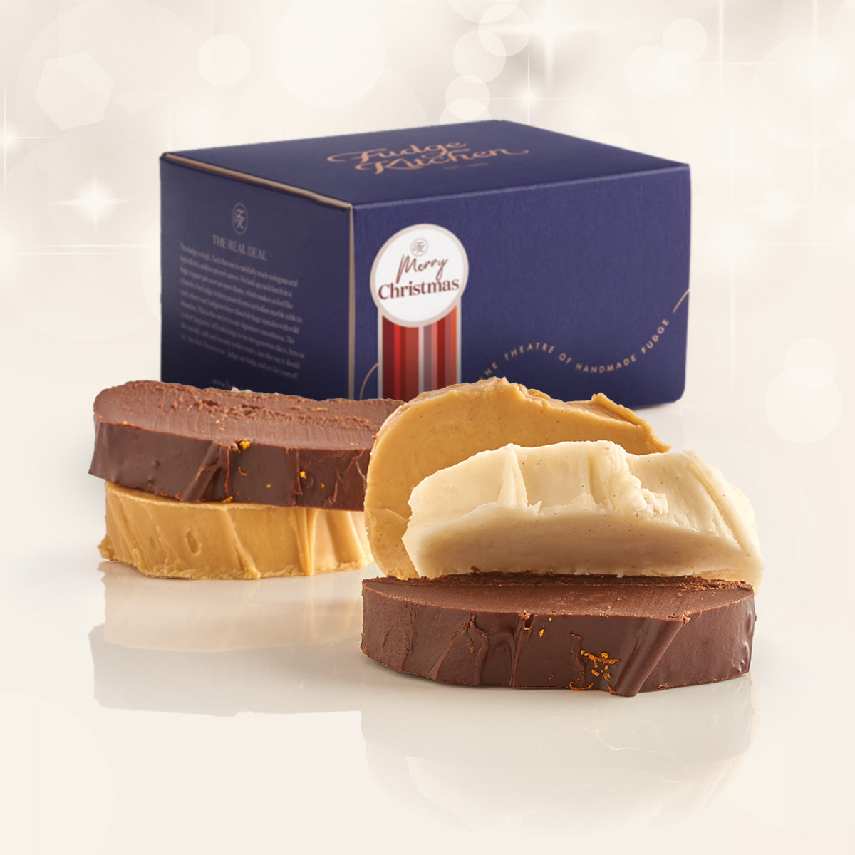 Christmas Fudge Selection showing 5 slices of fresh fudge in christmas flavours ldisplayed on a plain background with a luxury gift box behind with a Christmas Gift with Decorative Seal